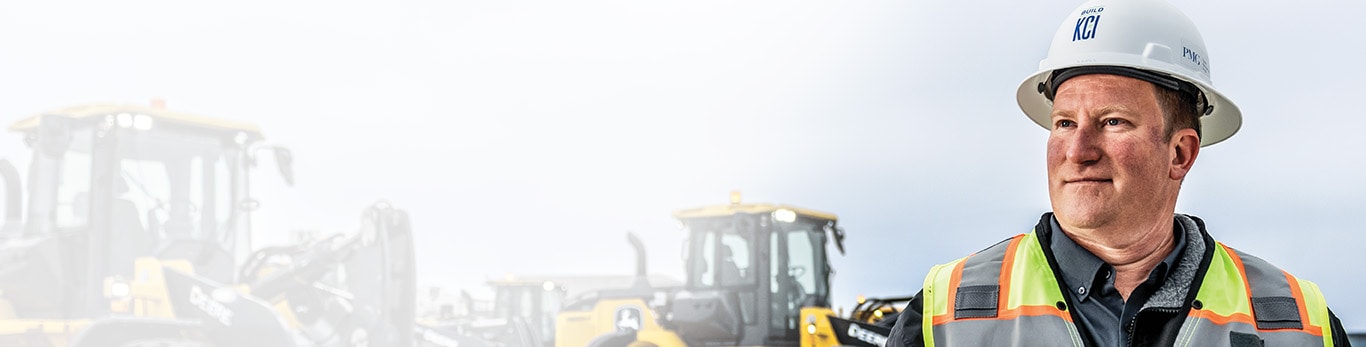 Aaron Kaden devant les chargeuses à roues 644 de catégorie X de John Deere à l’aéroport international de Kansas City.