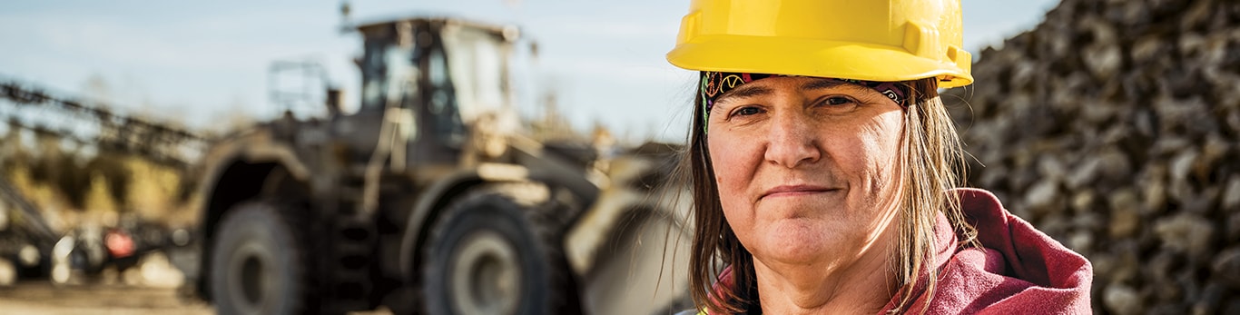 Portrait de Lisa Nanninga devant une chargeuse à roues de John Deere et une pile de roches