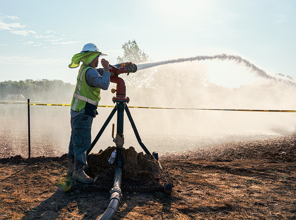 Clemente stands behind the water cannon spraying water on the dry dirt.