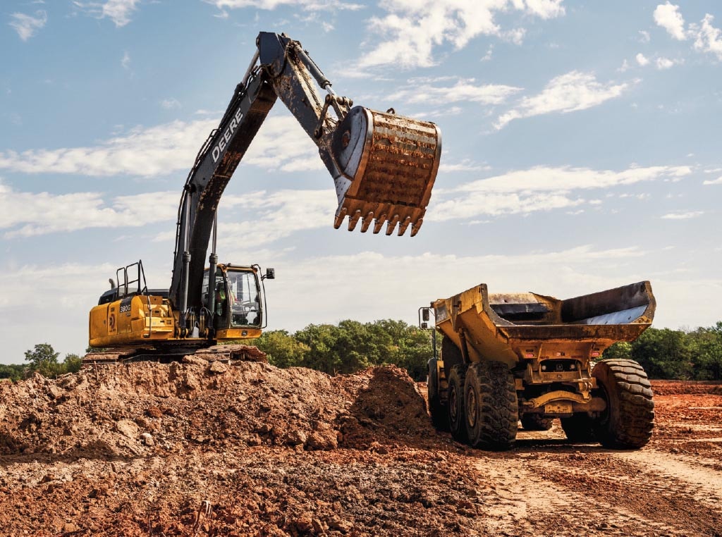 A 380G LC Excavator loads a bucketful of dirt into a 460E Articulated Dump Truck’s dump box.