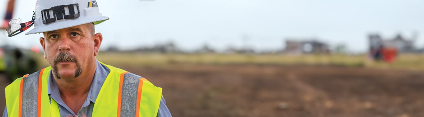 Travailleur portant un équipement de sécurité debout sur un chantier de construction.