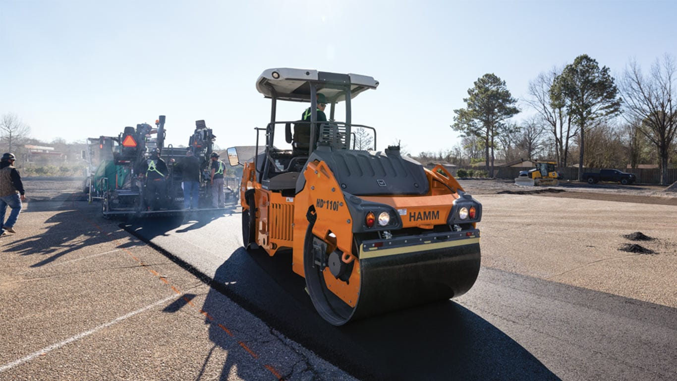 A pavement roller and pavement layer laying pavement on a work site
