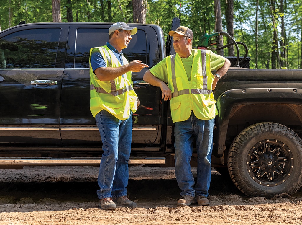 Leaning against a pickup truck, Brian talks with Doug.