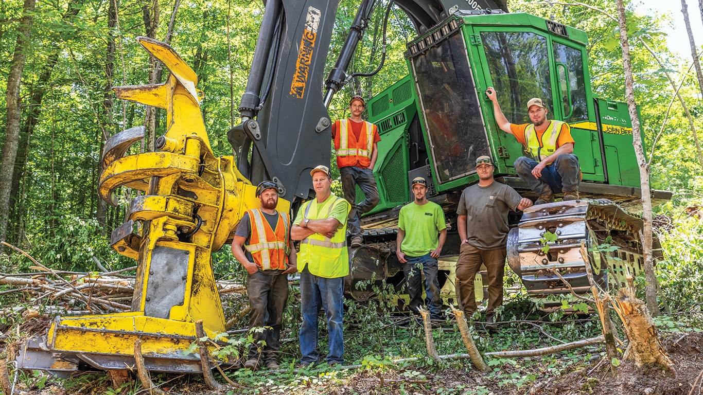 Dans les bois du Michigan, Max Tervo, Doug Anderson, Ladd Anderson, Nash Anderson, Eli Larson et Dane Anderson, tous de Doug Anderson Logging, se tiennent à côté d'une abatteuse-groupeuse chenillée 853M.