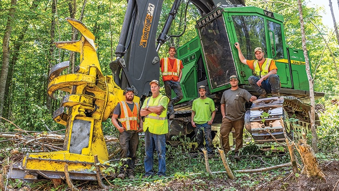 Max Tervo, Doug Anderson, Ladd Anderson, Nash Anderson, Eli Larson, and Dane Anderson, all of Doug Anderson Logging, pose beside a John Deere 853M Tracked Feller Buncher.