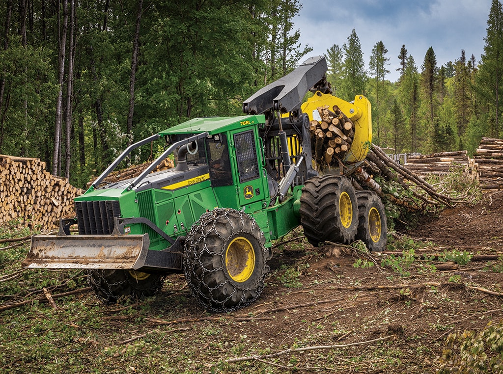 A 768L-II Bogie Skidder is dragging a load of logs in its grapple.