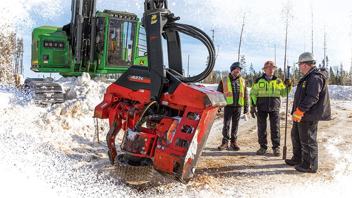 From left to right. Standing beside a John Deere 953MH Tracked Harvester are Allain Santerre, Louis Maher and Adam Williams.