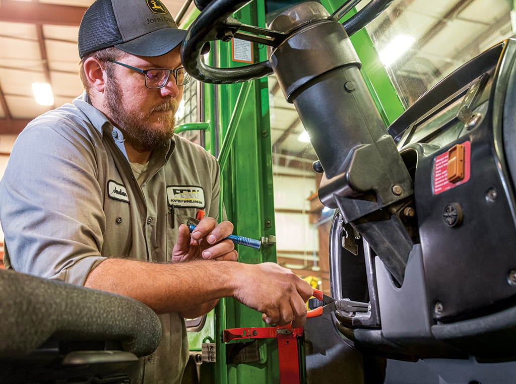 Jordan is installing replacement parts in the cab of the skidder.