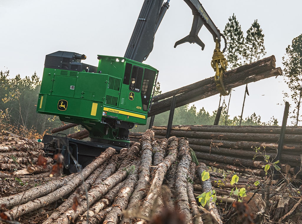 Le chargeuse à griffe 437E utilise son grappin pour déplacer les arbres abattus sur une remorque.