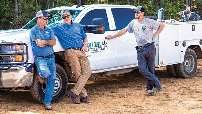 Randy Wilkes, représentant du concessionnaire Dobbs Equipment, s’entretient avec le père et le fils Bud West de Brown Chapel Logging et Matt West de West Forest Products.