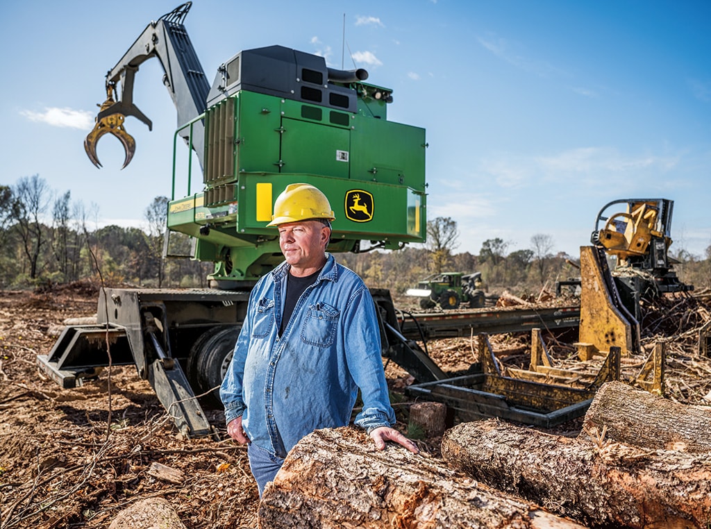 Larry rests his hand on a log as the big 437E Knuckleboom Loader prepares to move another load.
