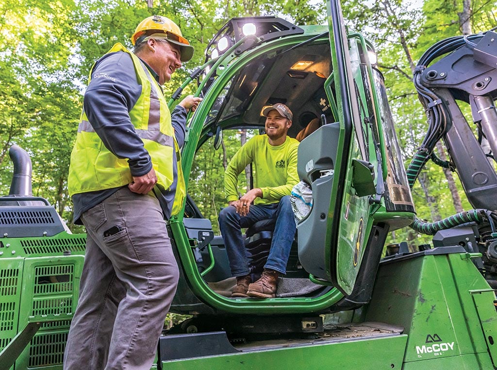 Jason Whitaker chats with Cody Harju as he sits in an 1110G Forwarder cab.