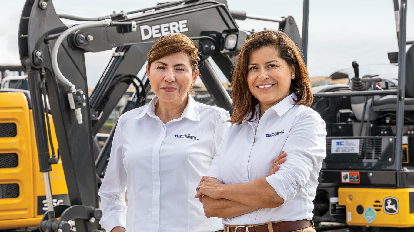 Lilia Jubrail et Ernestina Rincon se tiennent devant une pelle compacte 26G John Deere