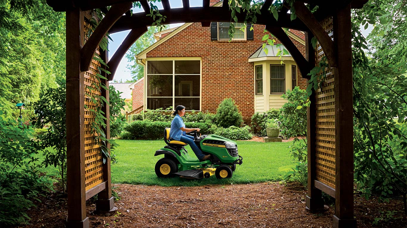 A woman mowing a tidy lawn and garden