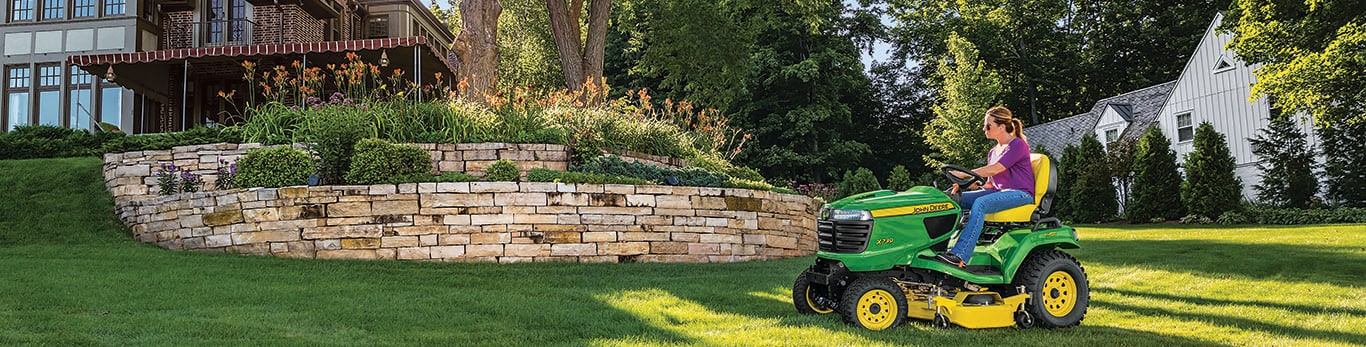 femme utilisant une tondeuse autoportée John Deere dans sa cour