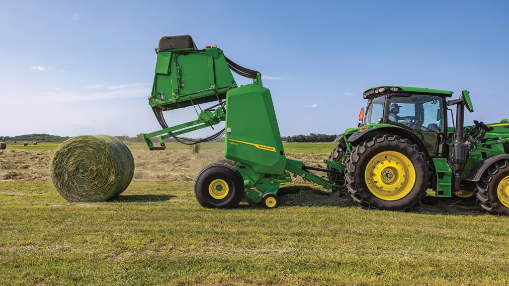 Tracteur 6R tirant une presse 461R qui éjecte une balle ronde