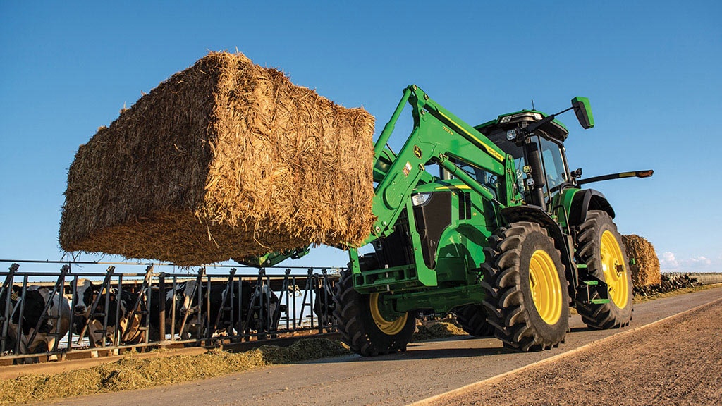 Tracteur 7R levant une balle de foin pour nourrir des vaches