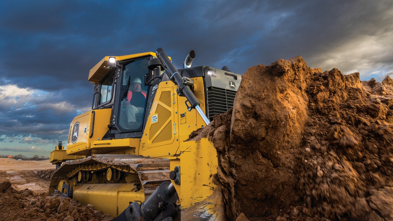 Bouteur chenillé 850L de John Deere poussant un monticule de terre sur le chantier.