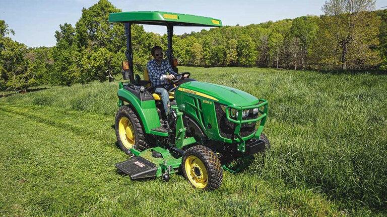 Homme tondant de l’herbe avec un tracteur 2032r