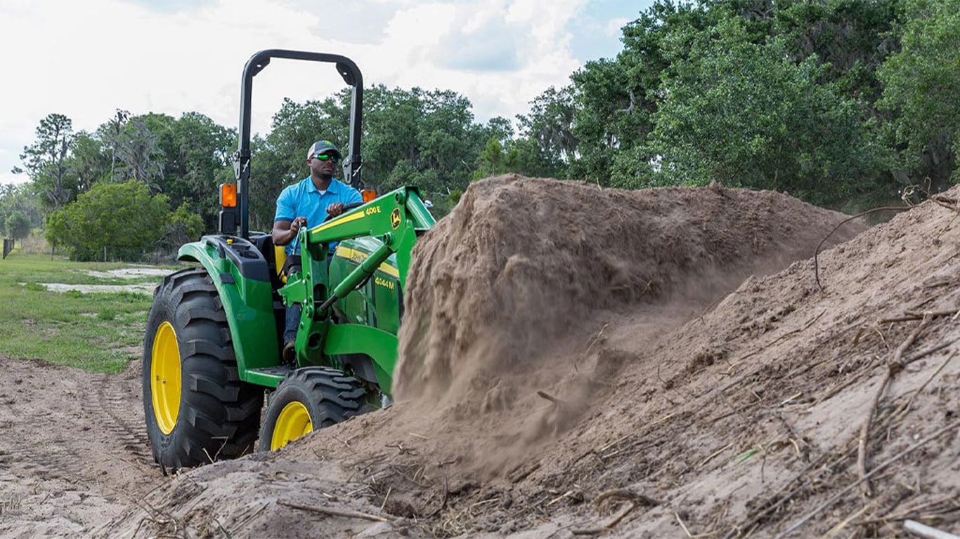 Homme sur tracteur 4044m, pelletage de terre