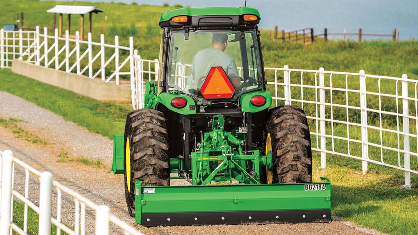 Homme conduisant un tracteur 4044R sur une route de campagne