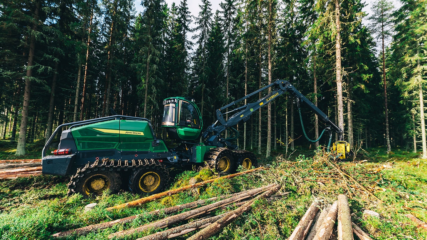 Abatteuse-façonneuse 1270H de John Deere fonctionnant dans une forêt dense, coupant des arbres avec le bras de précision.