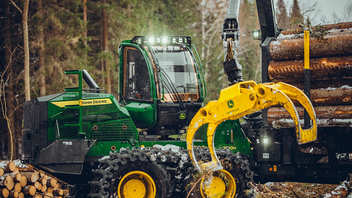Porteur 2510H de John Deere utilisant un grappin pour soulever des grumes dans un environnement forestier.