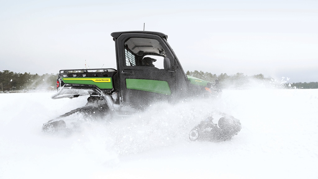 Un Gator&nbsp;XUV vert stationné sur du gravier devant quelques granges.