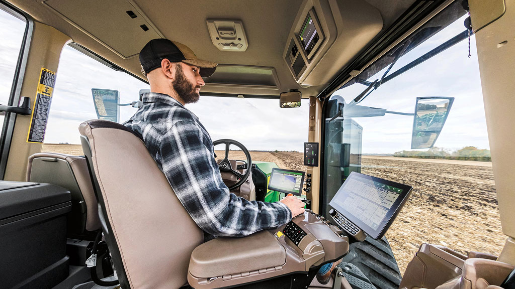 Une personne utilise AutoPath dans la cabine d’un tracteur dans un champ.