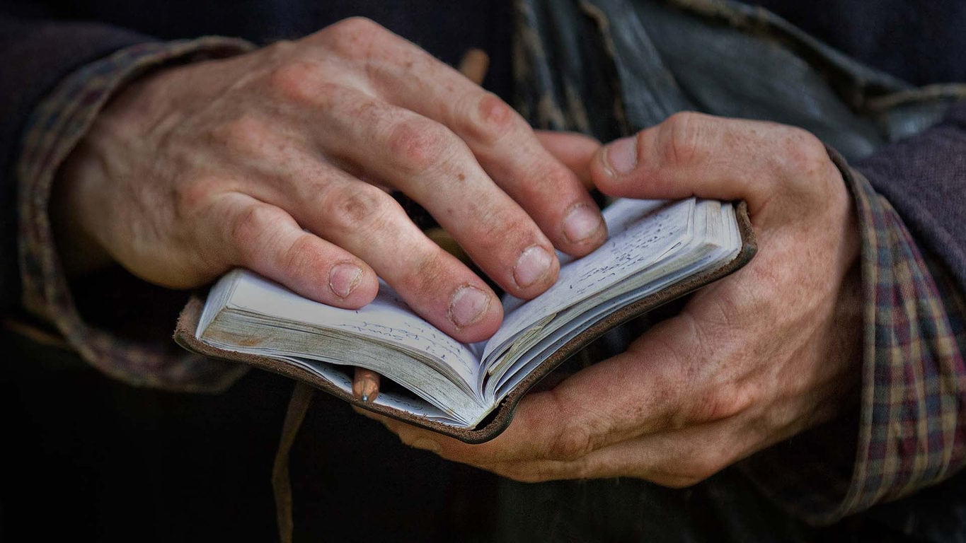 dirty hands flipping through a notebook