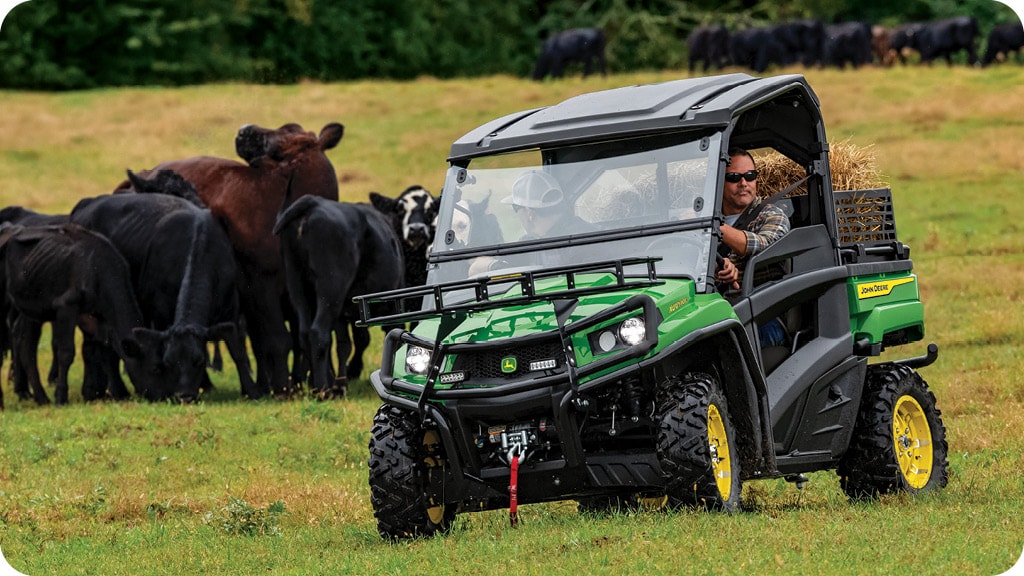 0% APR for 72 months advertisement showing a man in a John Deere XUV500 Series Gator utility vehicle driving near cattle.