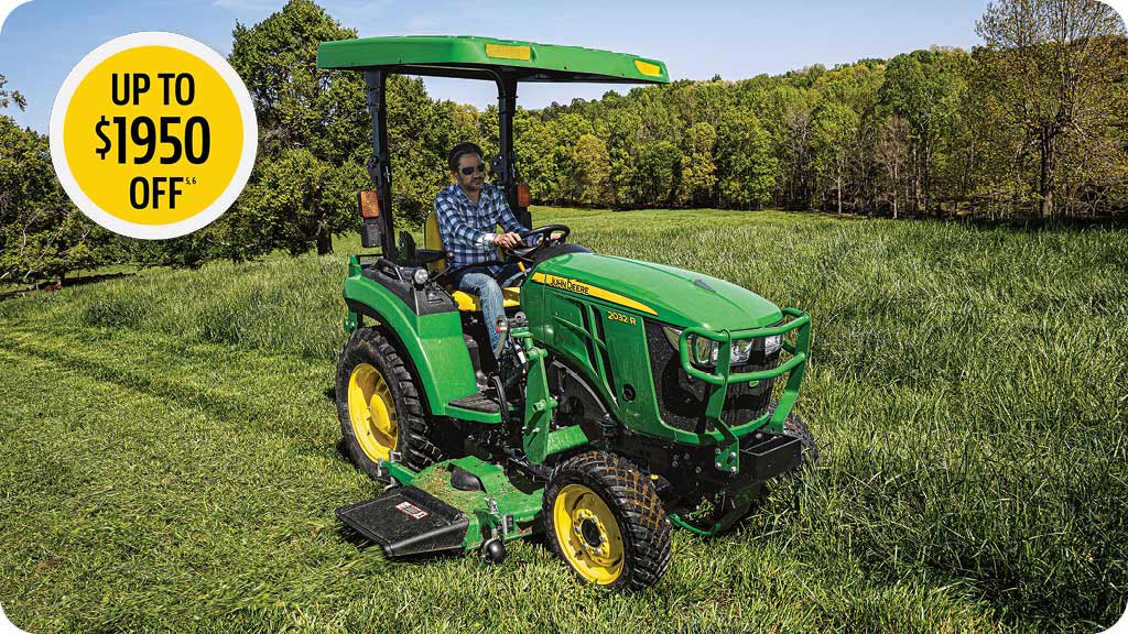 Man in the seat of a John Deere Series 2 compact tractor mowing tall grass.