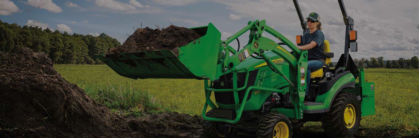 person on a 1025R compact tractor with 120R bucket attachment