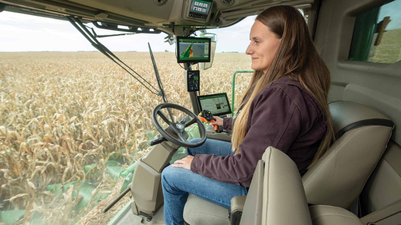 Combine operator harvesting corn field.