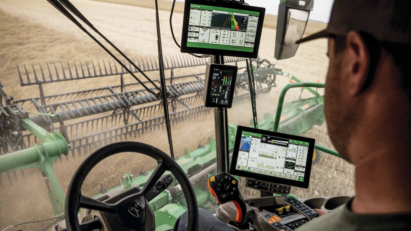  Inside cab view of a John Deere combine harvesting a field.