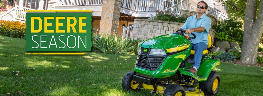 x330 John Deere lawn tractor cutting grass in yard near bushes