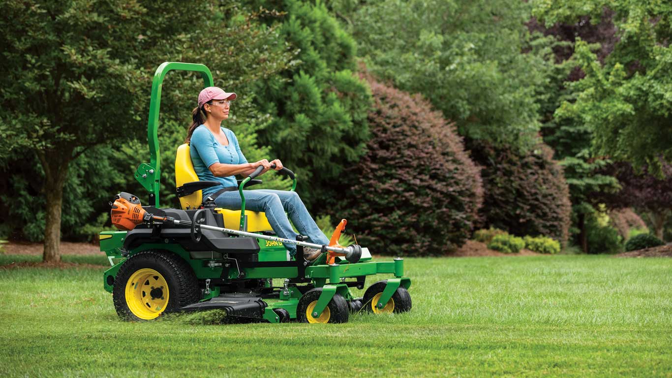 une femme tond l’herbe avec une tondeuse autoportée John Deere