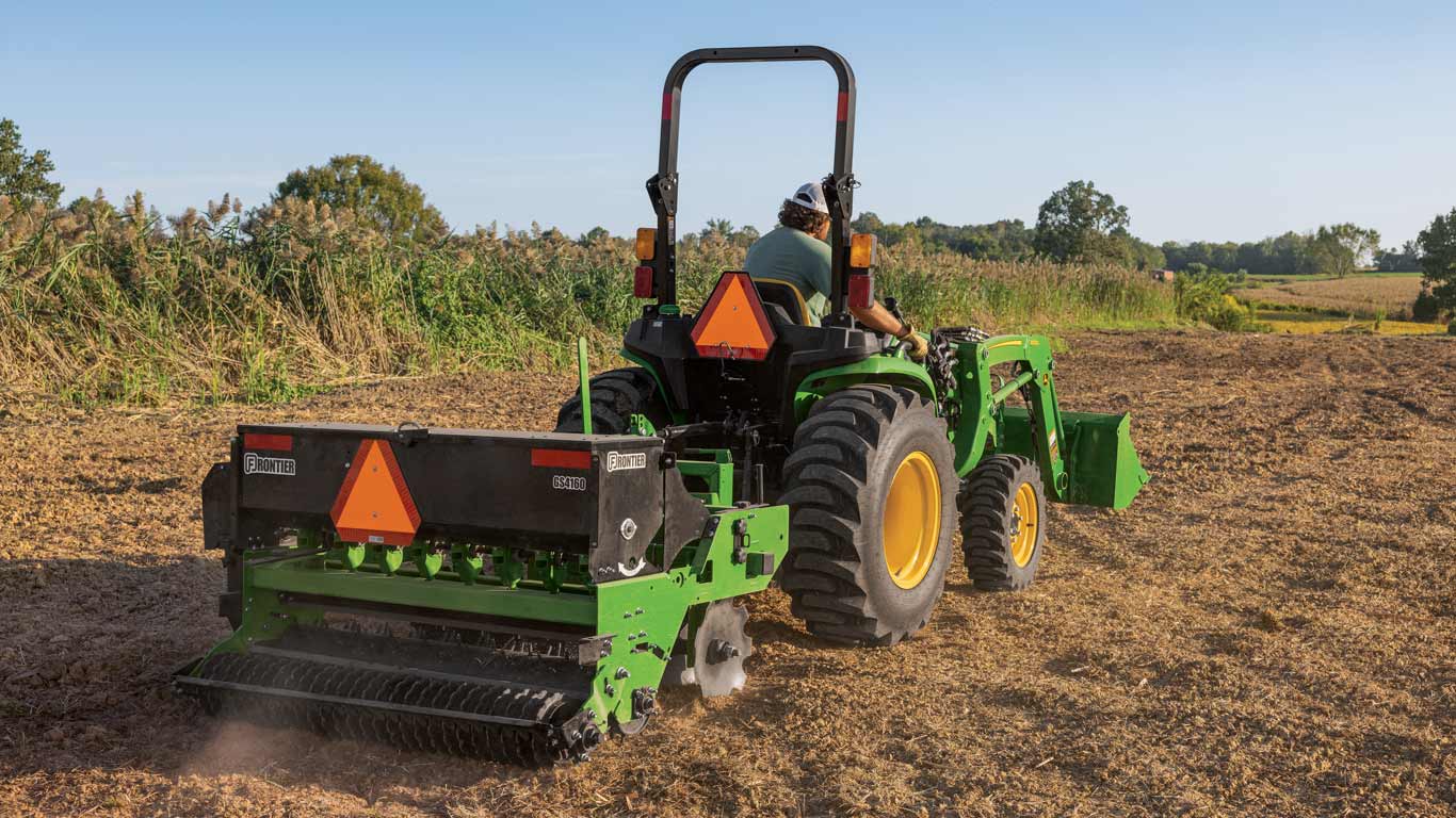 Instruments John Deere Frontier attachés à un tracteur dans un champ de terre