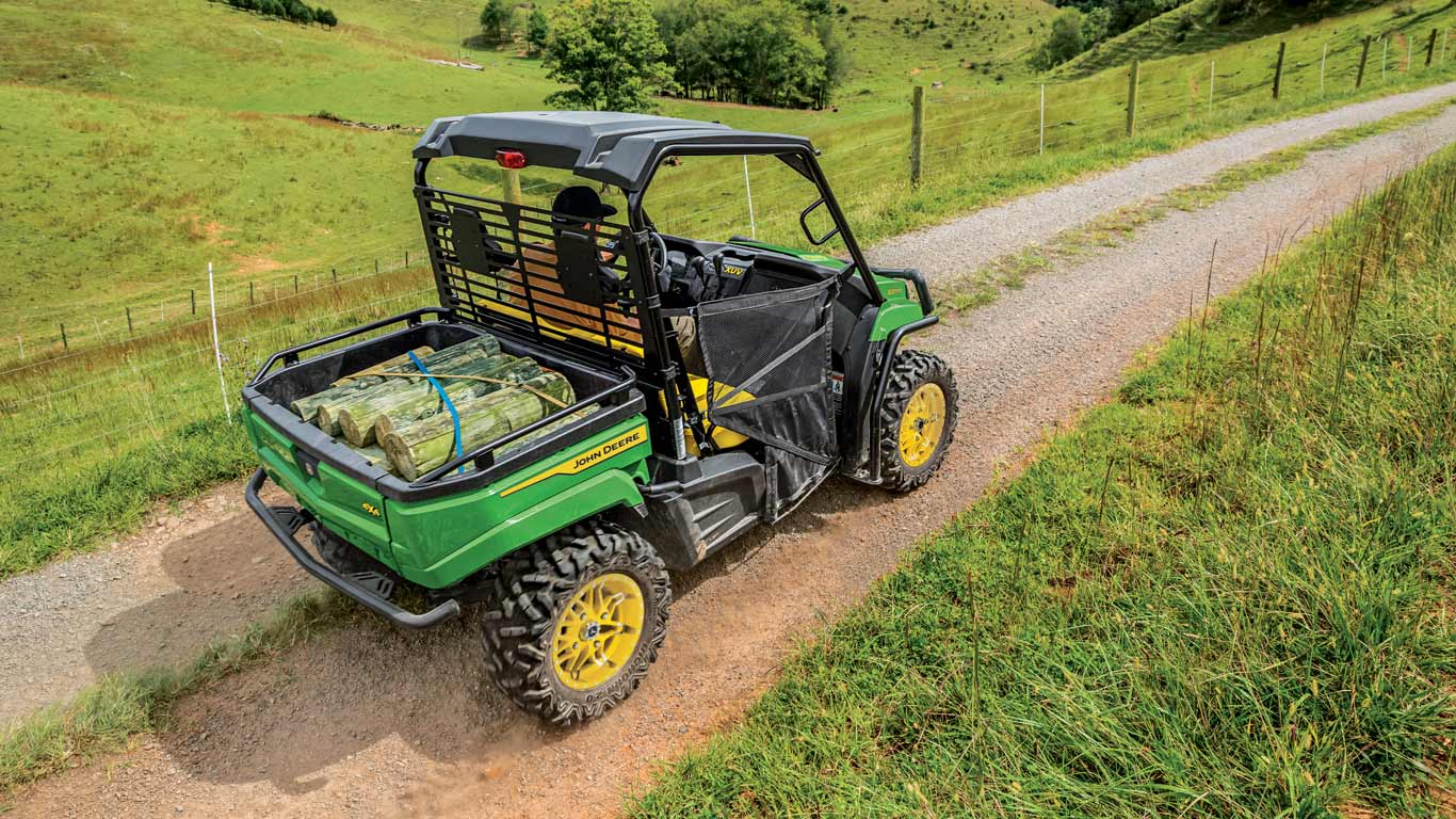 Véhicule utilitaire John Deere Gator XUV590M transportant une charge et roulant sur un chemin de gravier