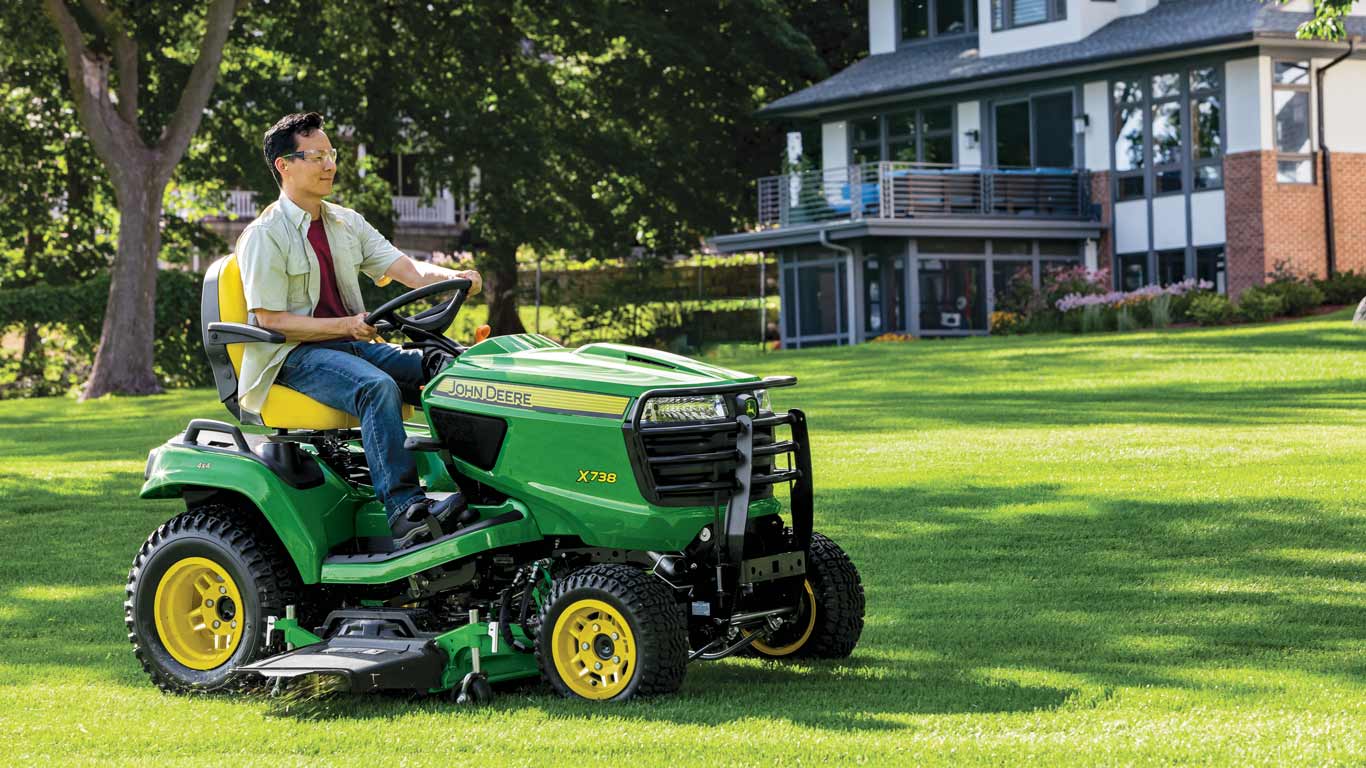un homme conduisant un tracteur de pelouse John Deere X738