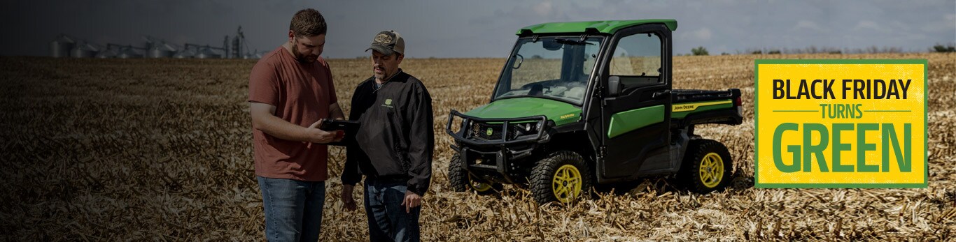 People in a field analyzing a tablet with a gator vehicle in background