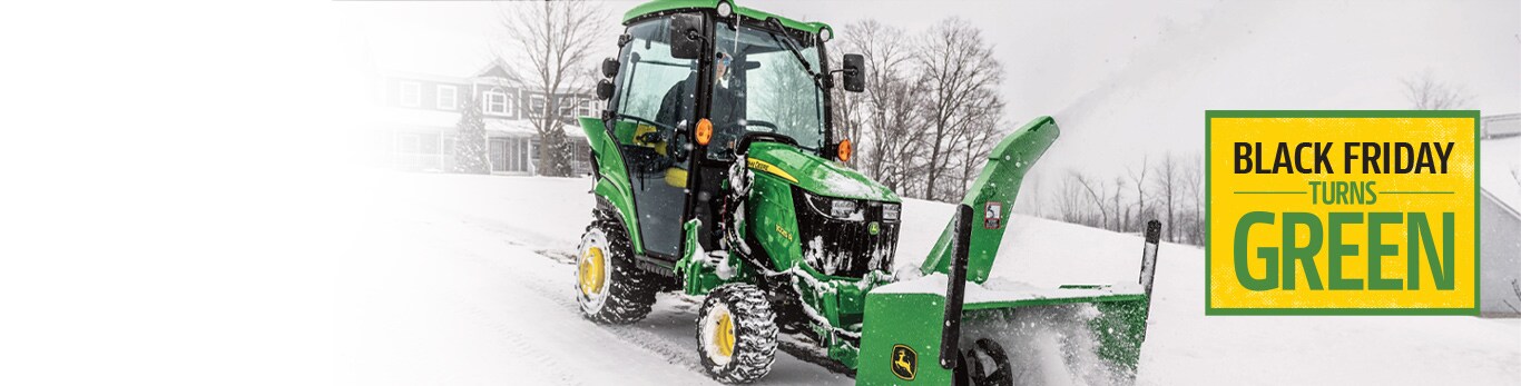 Person operating inside a 1025R Sub-Compact Tractor using a snow blower attachment