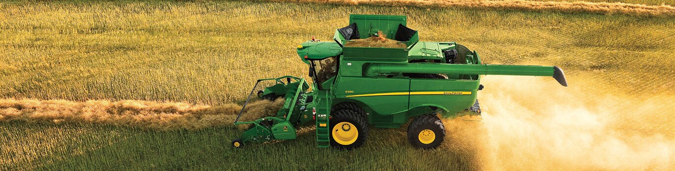 Moissonneuse-batteuse pour le grain John Deere S690 avec élément de récolte à tablier ramasseur à courroie 615P pour utilisation dans un champ