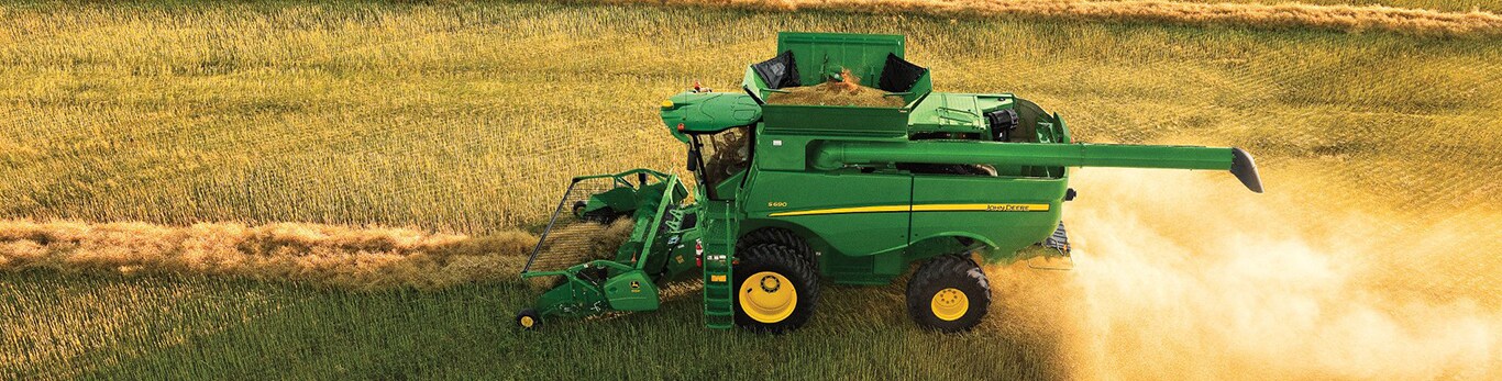 Moissonneuse-batteuse pour le grain John Deere S690 avec élément de récolte à tablier ramasseur à courroie 615P pour utilisation dans un champ