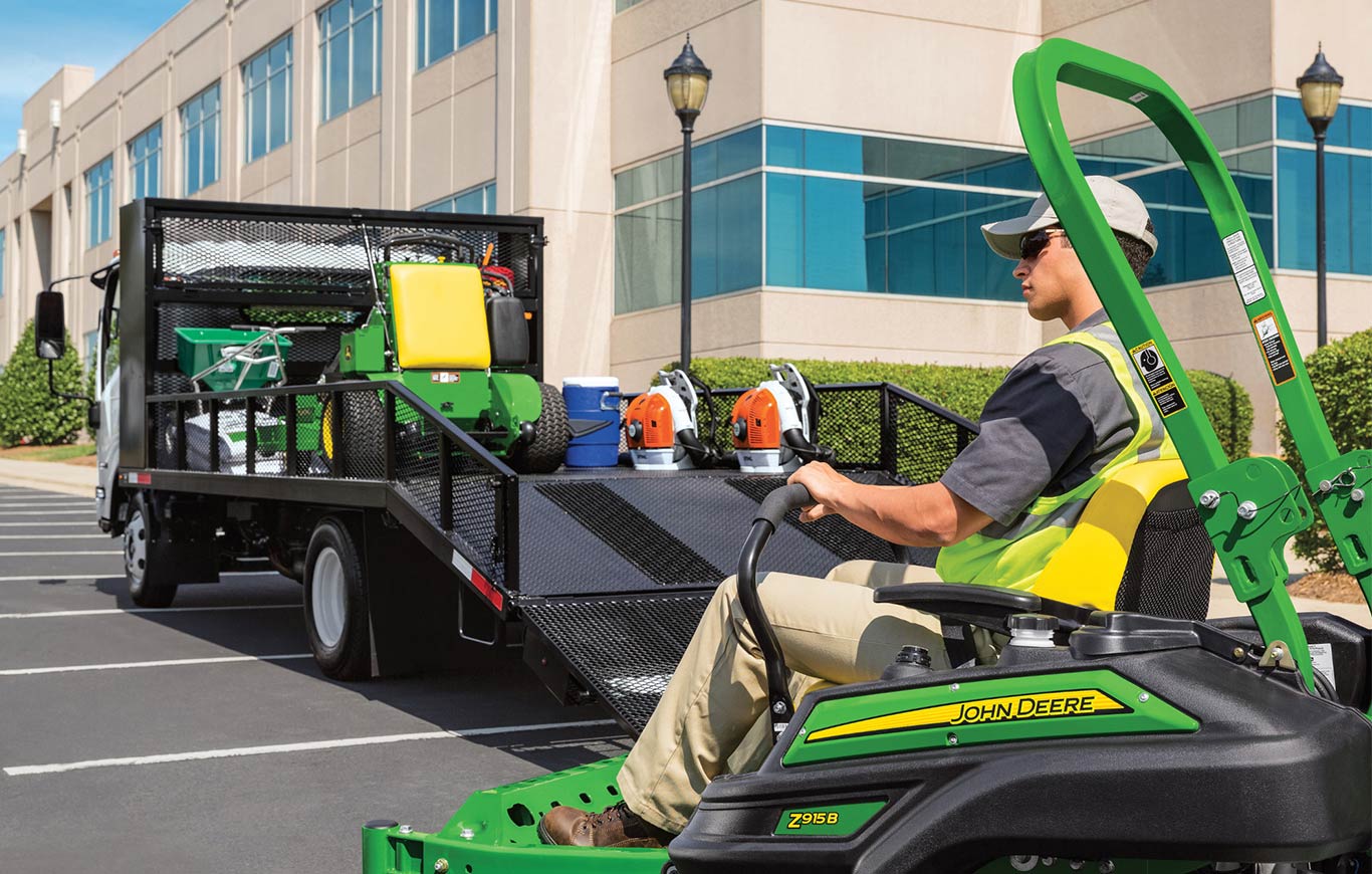 Professional landscaper unloading riding mower from trailer