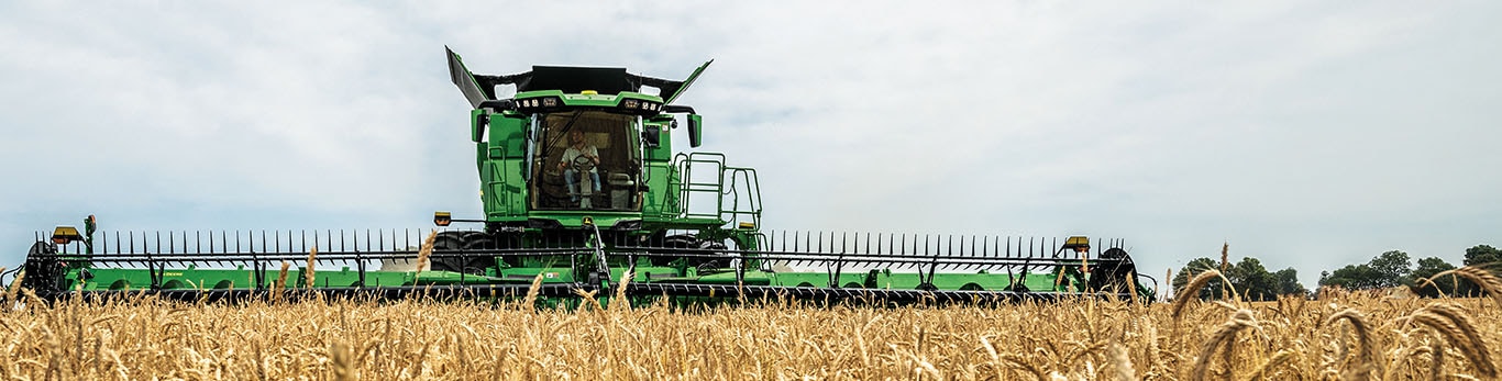 Photo grand-angle de face d’une moissonneuse-batteuse S7 John Deere avec tête de coupe de tablier à toile.