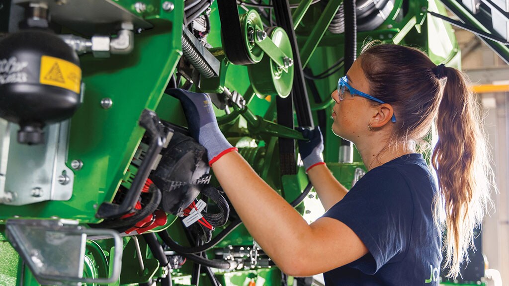 Technicien John Deere inspectant une moissonneuse-batteuse.
