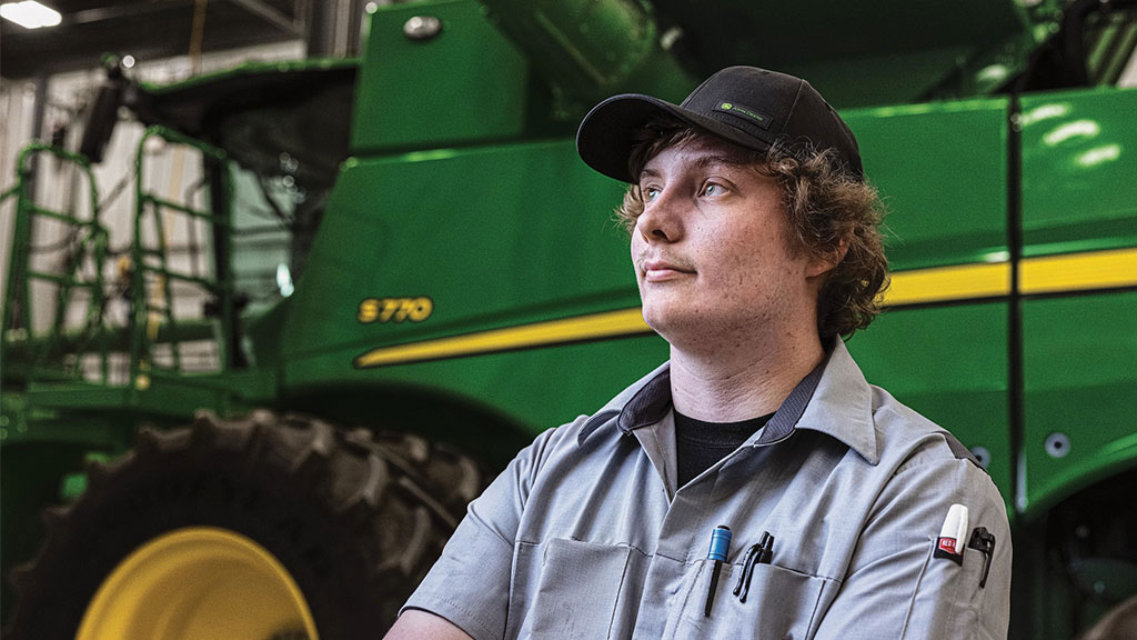 Technicien de service John Deere devant une moissonneuse-batteuse