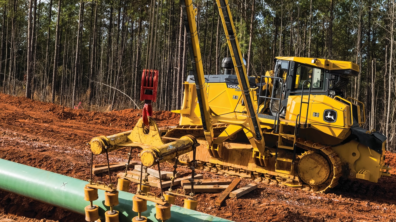 John Deere 1050K Crawler Dozer lifting a pipe.