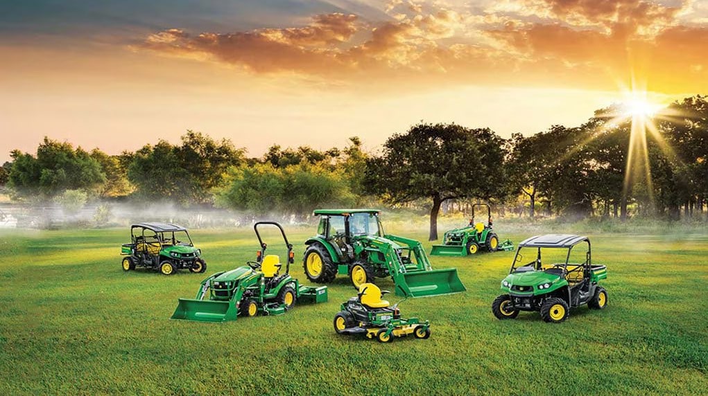 Des machines Gator, des tondeuses et des tracteurs verts dans un champ au lever du soleil.